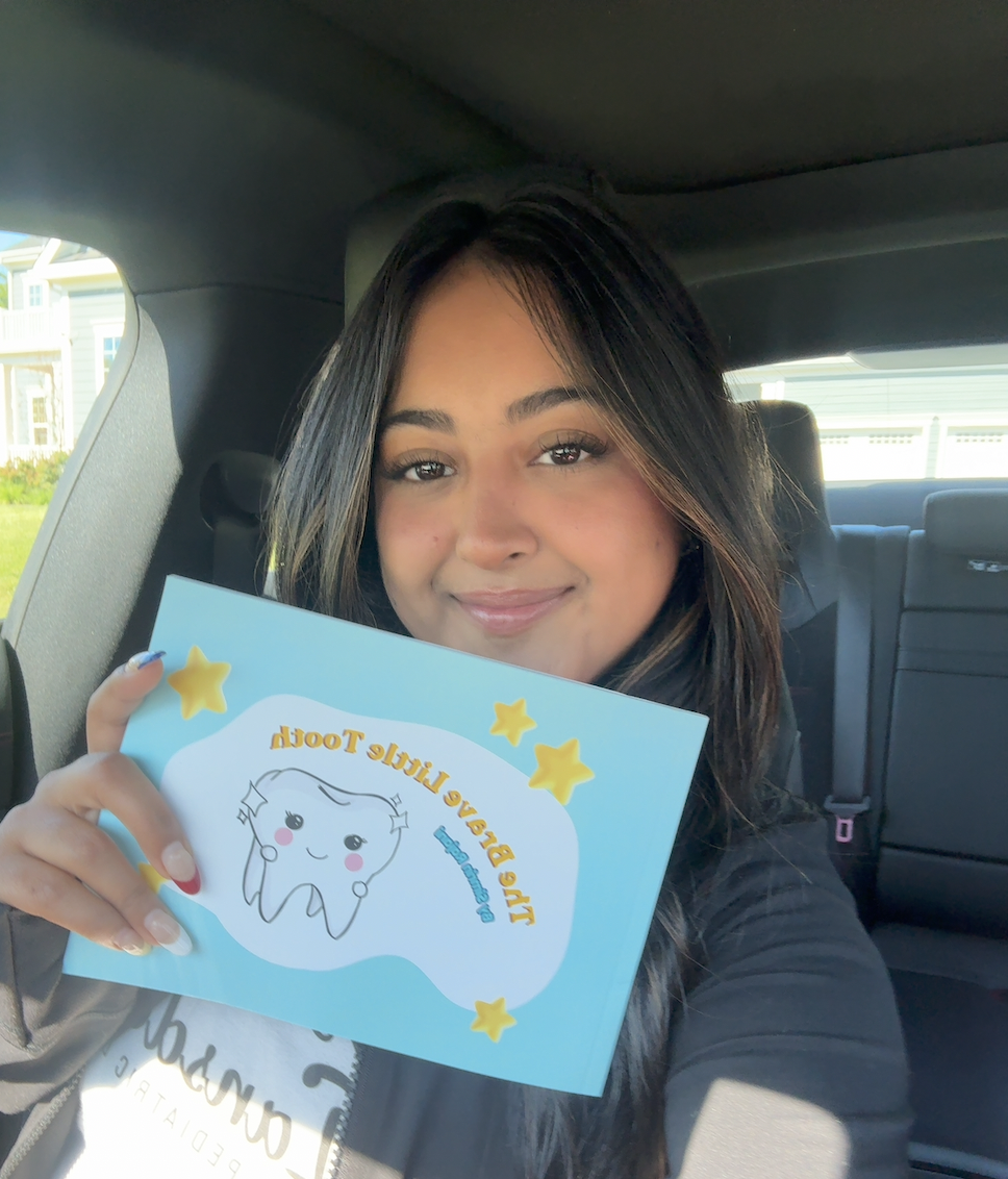 Simrin holding a printed copy of The Brave Little Tooth